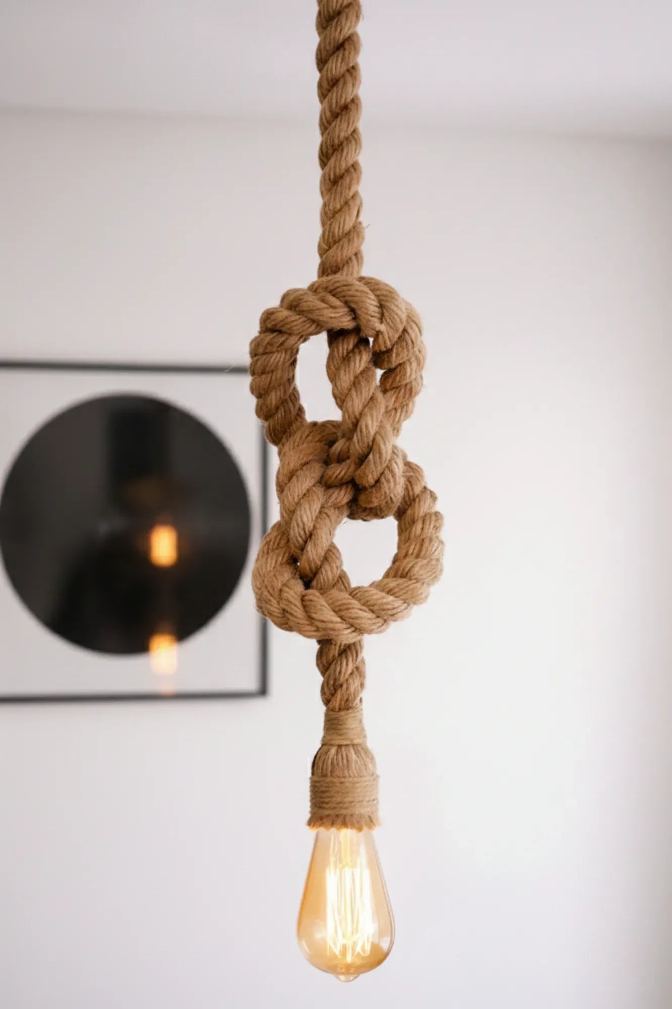 Detail van de handgeknoopte industriële touwlamp van jutetouw met warme lichtbron in een minimalistisch interieur