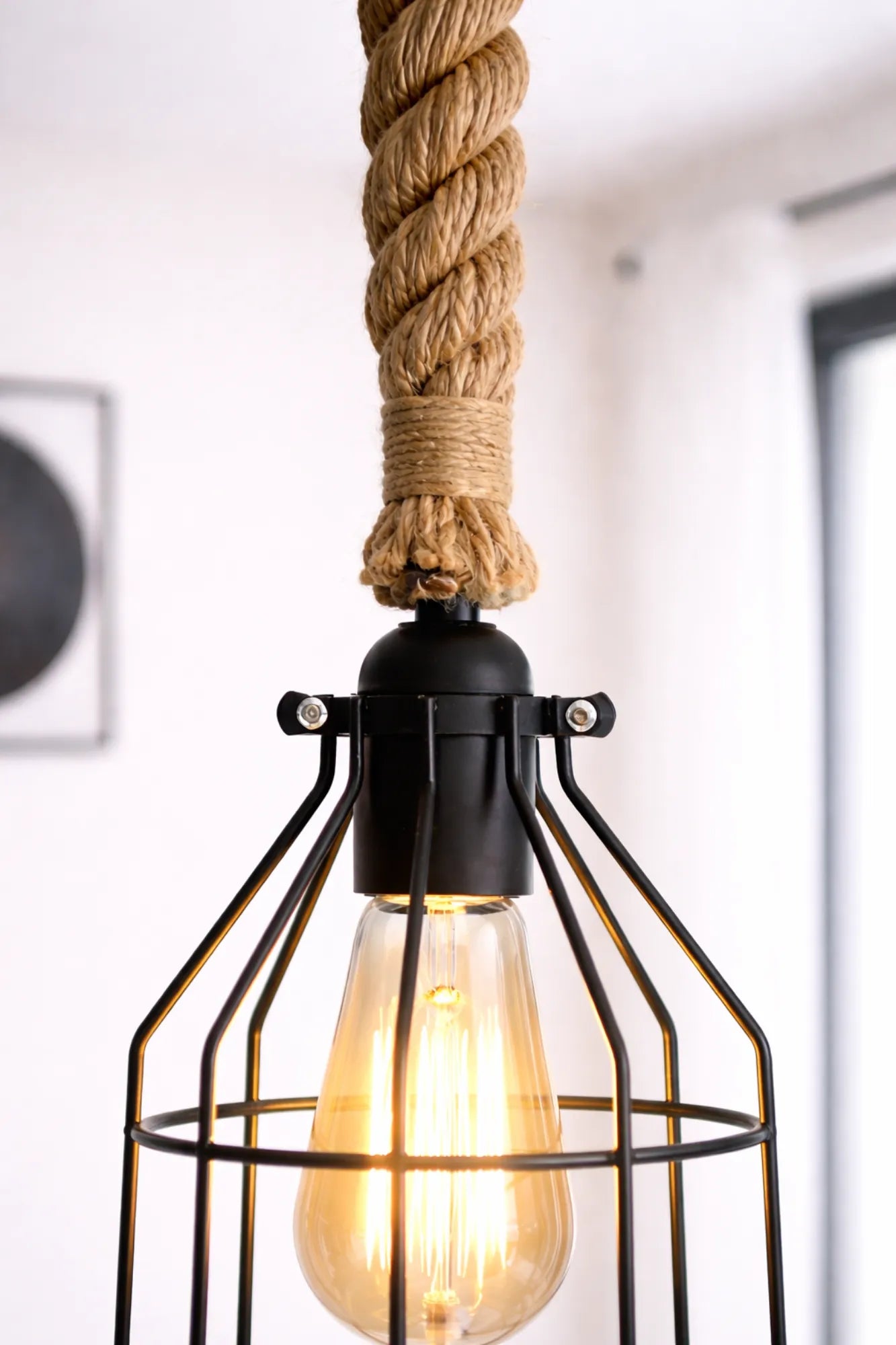 Detail van de zwarte fitting met metalen kooi en 30 mm jute touw van een industriële hanglamp