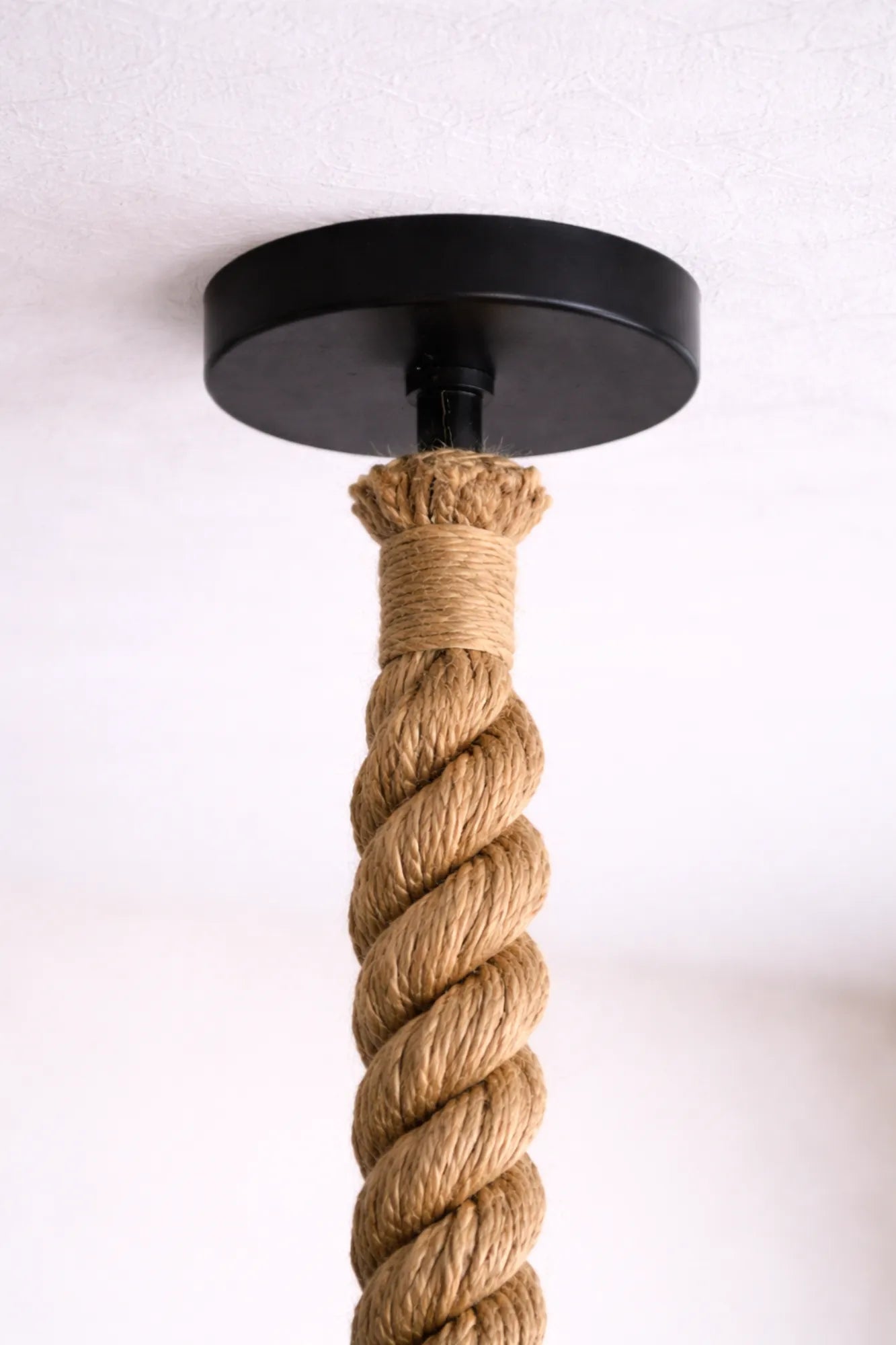 Detail van de zwarte plafondaansluiting met 30 mm jute touw van een industriële hanglamp