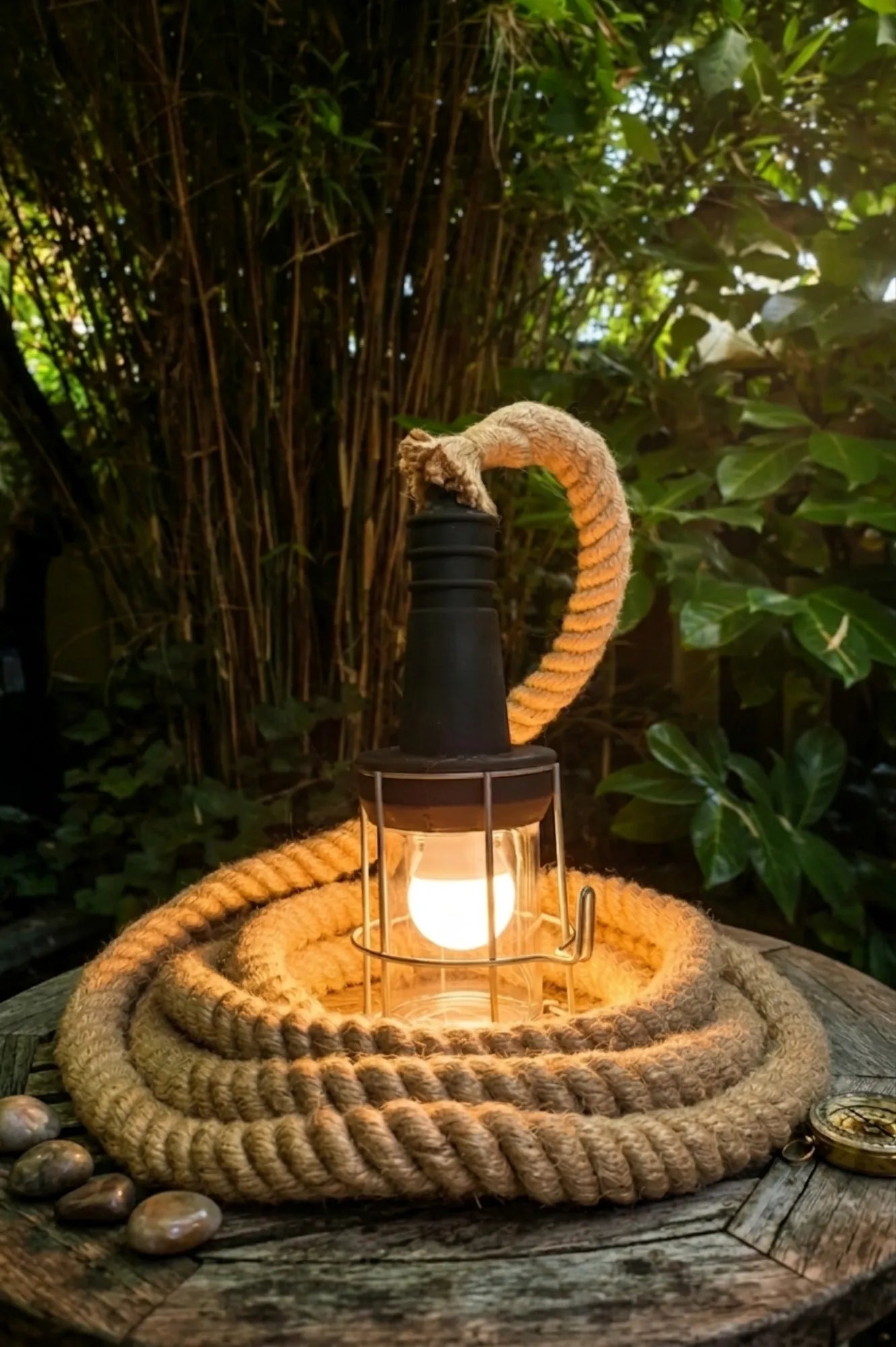 industriële buitenlamp met dik jutetouw en warme verlichting op rustieke houten tafel in groene tuinomgeving