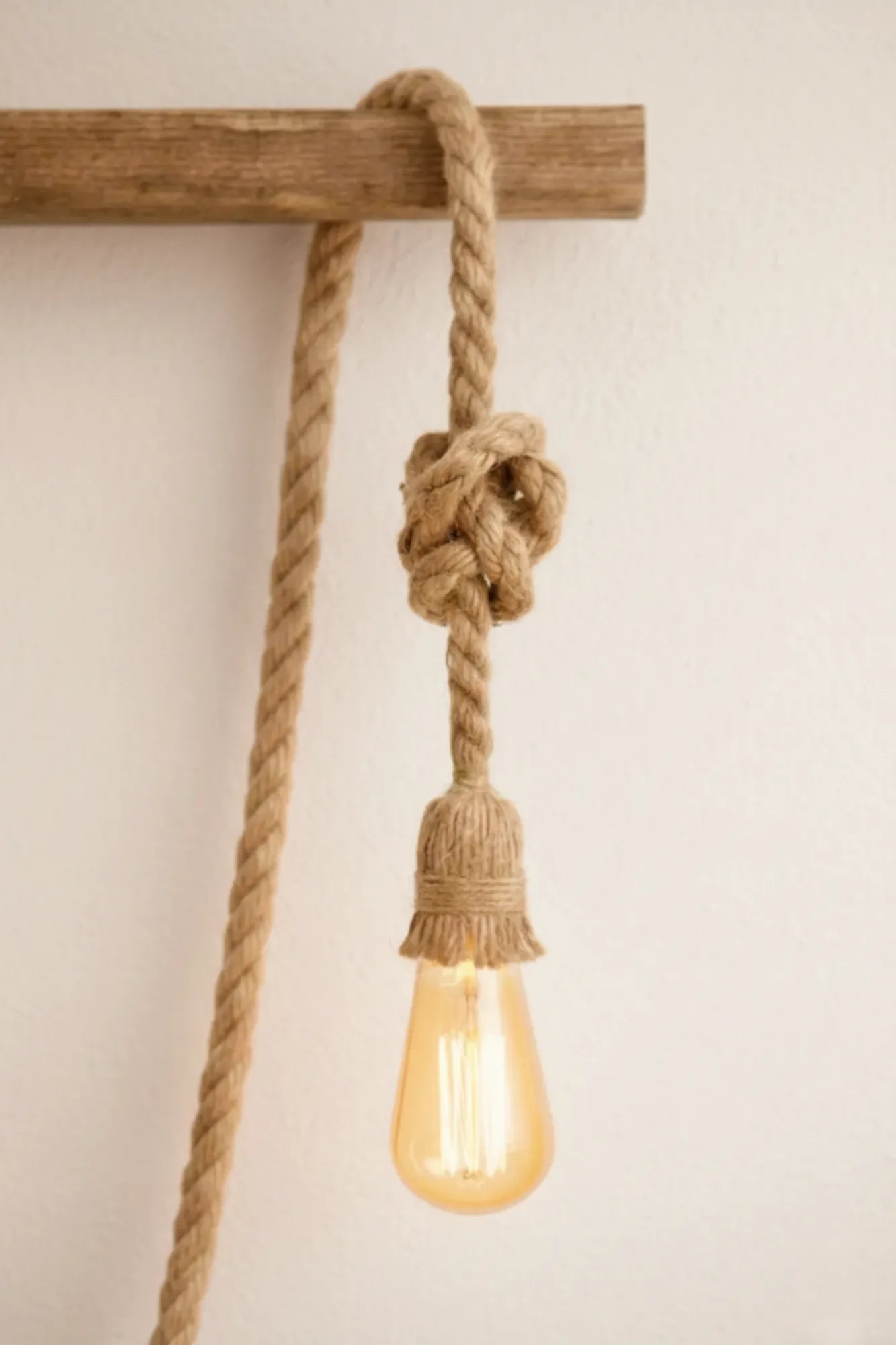 Detail van handgemaakte industriële touwlamp met enkele fitting, jute knoop en touwafwerking